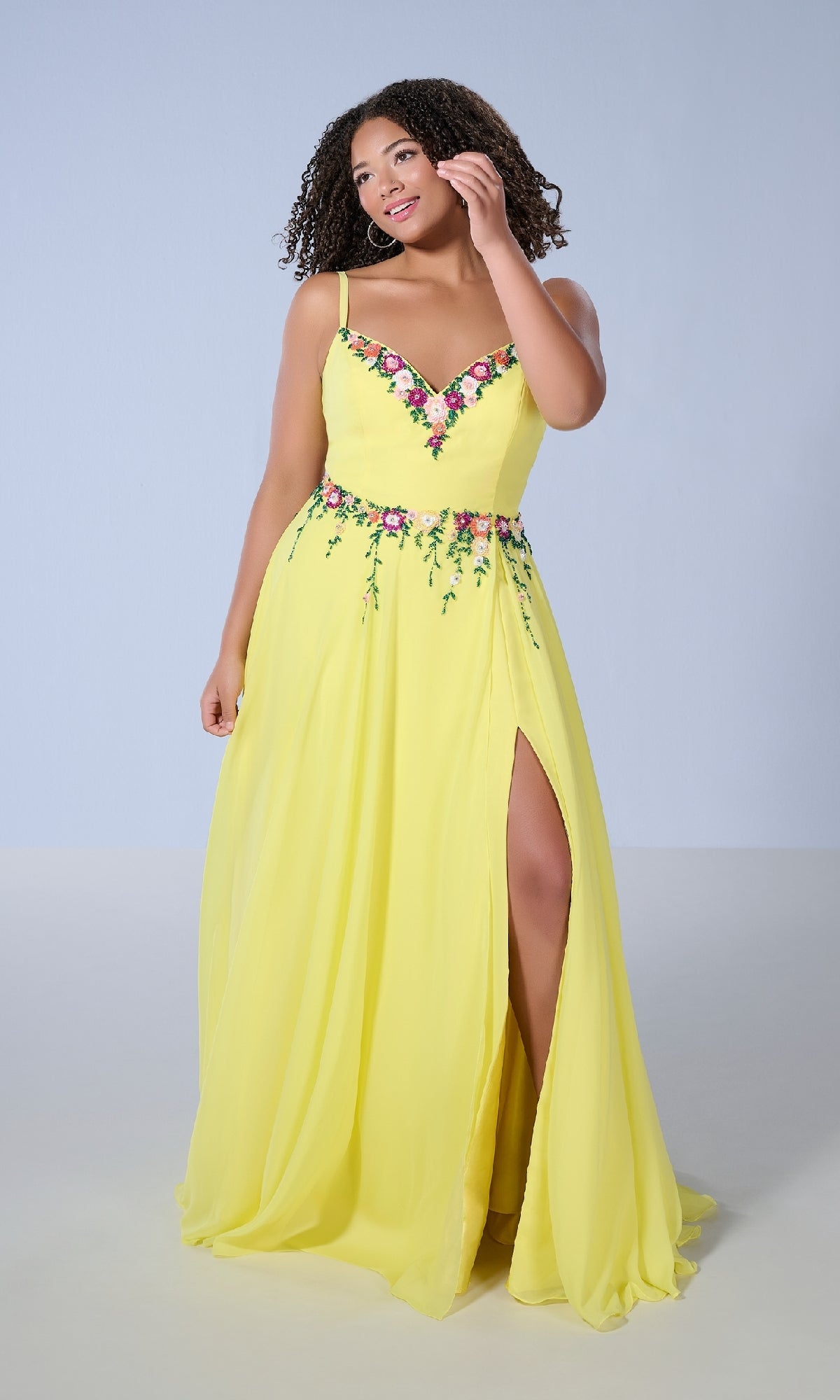 Model wears the Tiffany 16146, a long plus-size prom dress in bright yellow with floral beading at the neckline and waist, A-line skirt, and thigh-high slit, standing against a light backdrop.